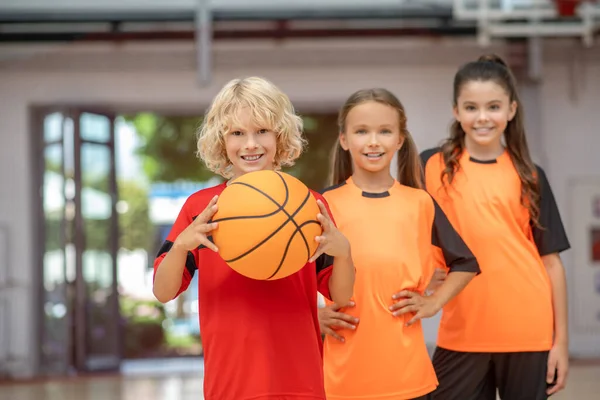 Niños en ropa deportiva de pie con una pelota y buscando disfrutado — Foto de Stock