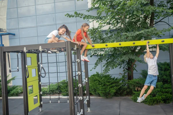 Blonde boy hanging on hands while his friends watching