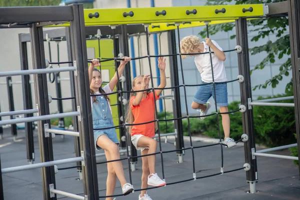 Kinderen klimmen op buiten speeltuin en kijken opgewonden — Stockfoto