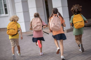 Sırt çantalı okul çocukları sabah okula gidiyor.