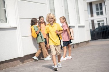 Sarı tişörtlü tatlı çocuk yürüyor ve gülümsüyor.