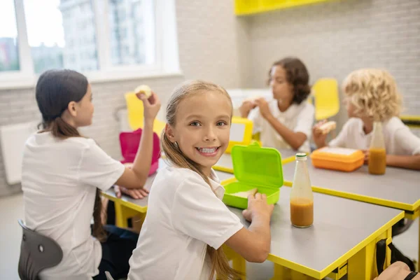 Los escolares almorzando en la clase y luciendo emocionados —  Fotos de Stock