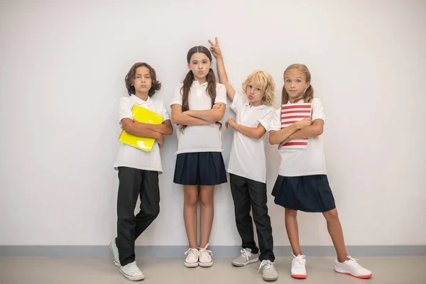 Niños de la escuela de pie cerca de la pared y sintiéndose como un equipo — Foto de Stock