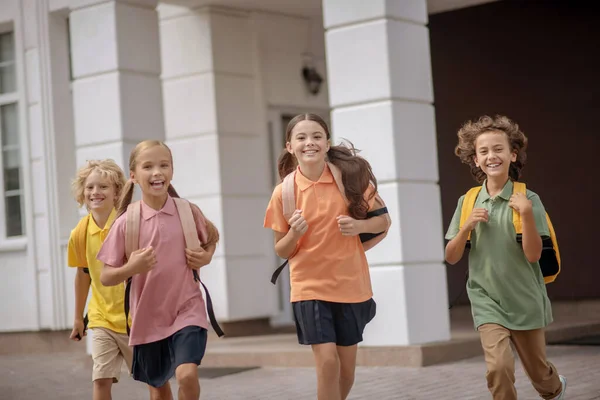 Écoliers avec sacs à dos courant à la maison après les cours — Photo