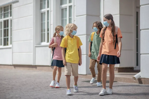 Group of schoolchildren in protective masks on their way home after lessons — Stock Photo, Image