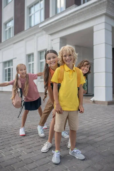 Schoolchildren meeting after lessons in school yard and feeling playful — Stock Photo, Image