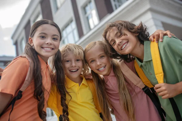 Les écoliers debout dans la cour de l'école et regardant joyeux — Photo