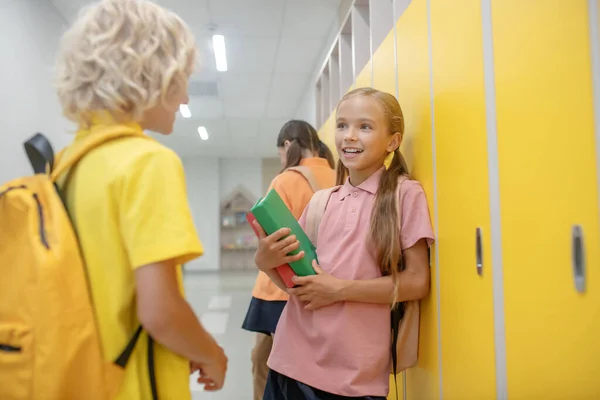 Garçon et fille parlent dans le couloir debout près des casiers — Photo