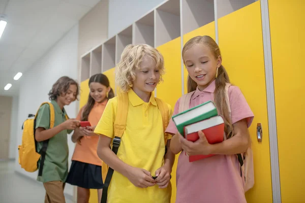 Słodkie dziewczyna pokazując jej książki dla blondynka chłopiec w żółty tshirt — Zdjęcie stockowe
