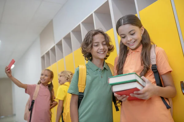 Cute girl showing her books to a boy in green tshirt — Stock Photo, Image