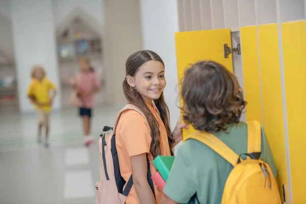 Mörkhårig tjej pratar med sin klasskamrat och ler — Stockfoto