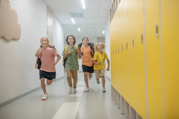 Happy schoolchildren running in the school corridor after lessons — Stock Photo, Image