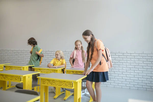 Cuatro niños con mochilas entran en el aula y se preparan para las lecciones — Foto de Stock