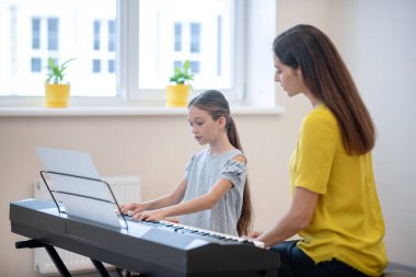 Şirin kız öğretmeniyle müzik dersi alıyor.