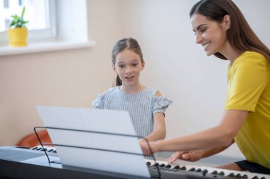 Bir kız ve öğretmeni müzik dersine olumlu bakıyor.