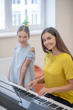 Güzel bir kız ve müzik öğretmeni memnun görünüyorlar.