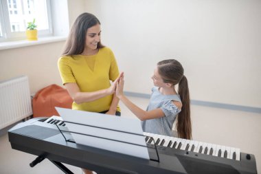 Kız ve öğretmeni piyanonun başında birlikte oturuyorlar.