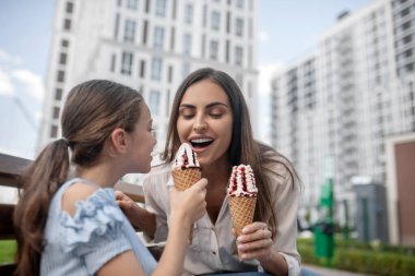 Anne ve kızı dondurma yiyor ve mutlu görünüyorlar.