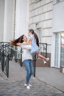 Koyu saçlı anne mutlu çocuğunu kucağında tutuyor ve kendini harika hissediyor.