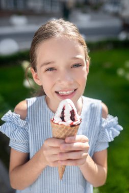 Tatlı gülümseyen çocuk dondurma tutuyor ve mutlu görünüyor.
