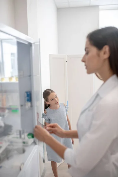 Grazioso dottore in camice da laboratorio che apre una vitrina con delle medicine — Foto Stock