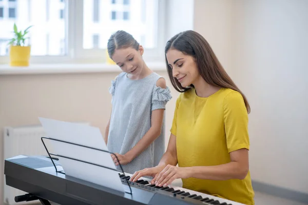 Een mooi meisje met een muziekles bij haar leraar en op zoek naar interesse — Stockfoto