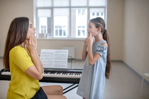 Meisje in blauwe jurk en haar leraar doen voice oefeningen — Stockfoto