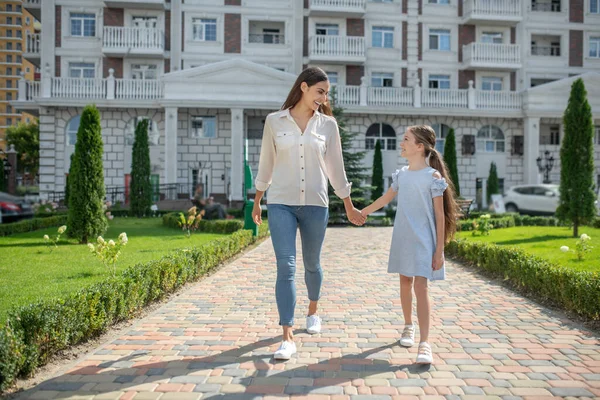 Anne ve kızı yürüyor ve el ele tutuşuyorlar