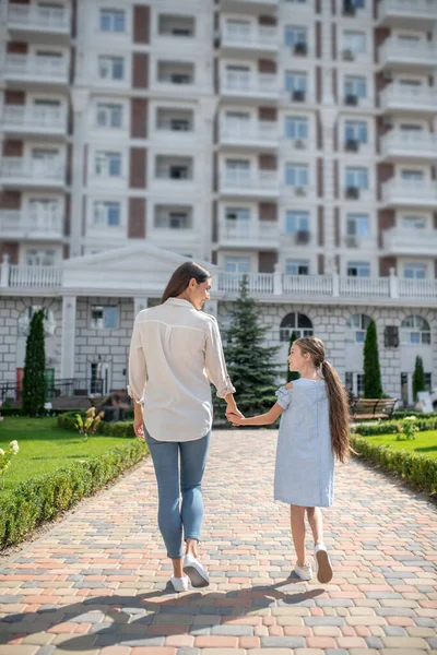 Genç anne ve kız el ele tutuşuyorlar.