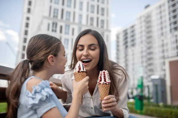 Anne ve kızı dondurma yiyor ve mutlu görünüyorlar.