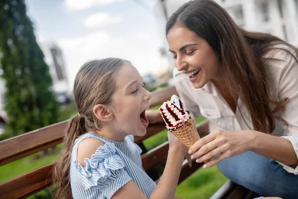 Mom and daughter eating ice-cream and having fun
