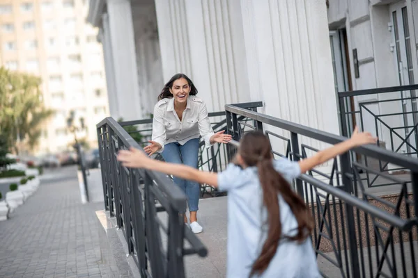 Flicka i blå klänning springer till sin mammas armar — Stockfoto