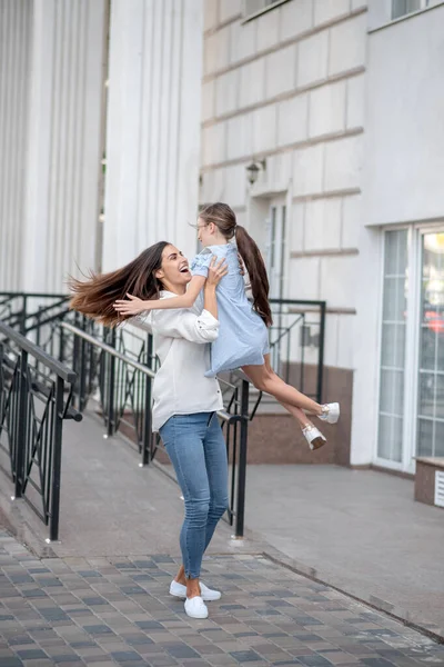 Koyu saçlı anne mutlu çocuğunu kucağında tutuyor ve kendini harika hissediyor.