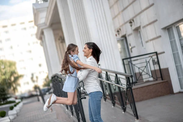 Dark-haired smiling mom holding her happy kid and feeling good — Stock Photo, Image