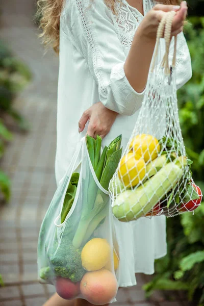 Vrouw in witte jurk draagtas met verschillende groenten — Stockfoto