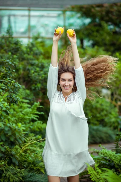 Женщина в белом платье бегает с лимонами в руках и чувствует себя размахивающей — стоковое фото