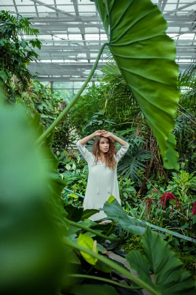 Kvinna i vit klänning stående i växthuset — Stockfoto