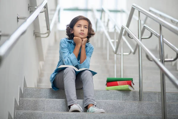 Boy with sad face sitting on steps of stairs