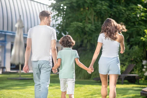 Man kvinna och skolbarn promenader med tillbaka till kameran — Stockfoto