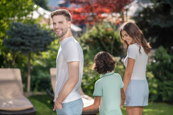 Ung man vänder sig mot kameran, går med sin son och hustru — Stockfoto