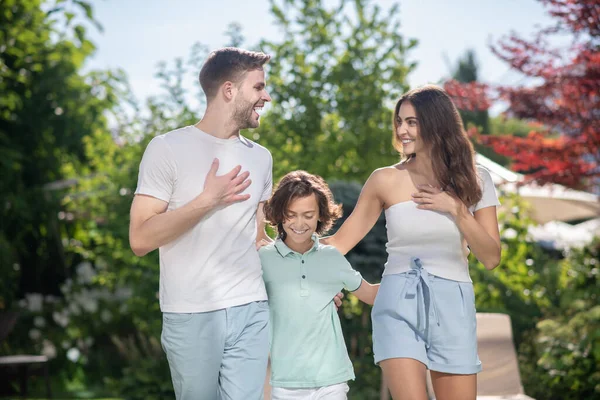 Familj på tre personer som omfamnar varandra, går ut och pratar. — Stockfoto