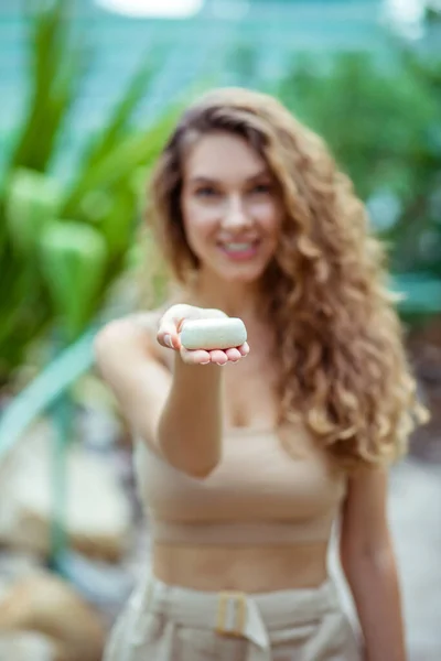 Pretty woman with long hair showing a bar of soap — Stock Photo, Image