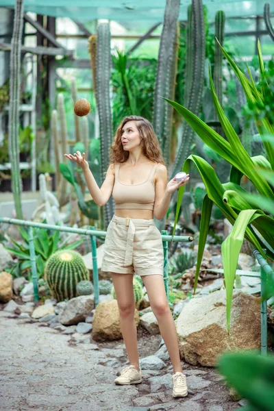 Cute woman holding a coconut and a jar of cream — Stock Photo, Image