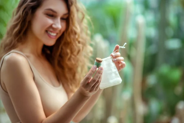 Mujer joven poniendo caja de sombra de ojos en bolsa ecológica — Foto de Stock