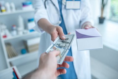 Müşteri eczanede laboratuvar önlüğü giyen birine para veriyor.