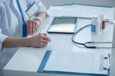 Laboratuvar önlüklü doktor masada oturuyor ve belgelerle uğraşıyor.