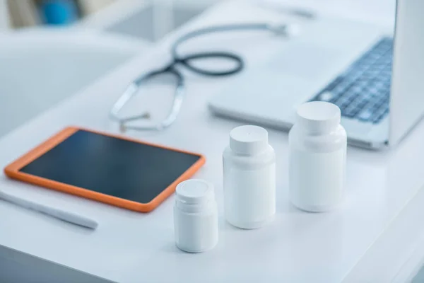 Frascos brancos com medicamento e um comprimido na mesa — Fotografia de Stock