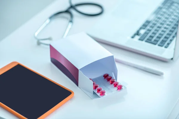 Blister con pillole rosse e dispositivi sul tavolo — Foto Stock