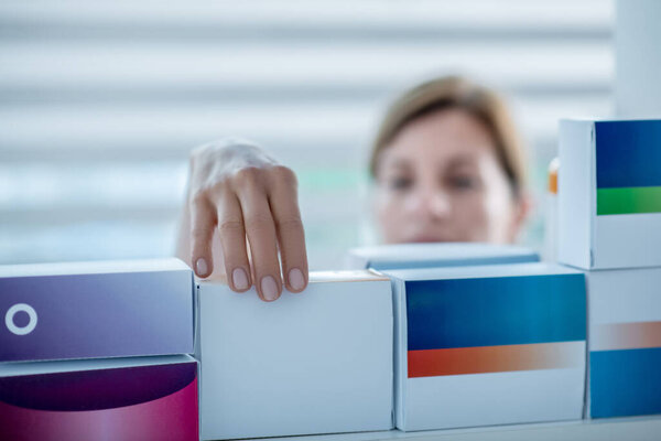 Крупный план аптекаря, берущего лекарство с полки