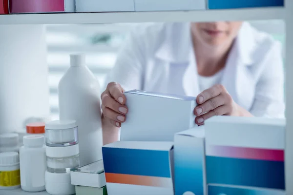 Farmacéutico tomando un medicamento de la estantería de la farmacia —  Fotos de Stock